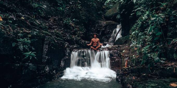 A man practices yoga on a waterfall at Oxygen Jungle Villas