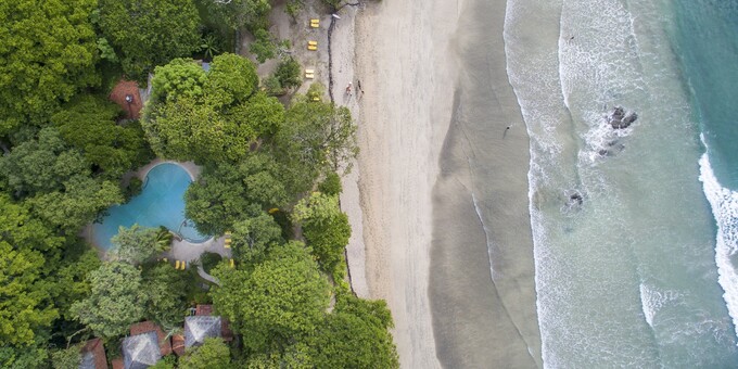 Hotel Capitan Suizo is a charming beachfront hotel nestled in the enchanting town of Tamarindo, Costa Rica. Surrounded by lush tropical gardens and boasting direct access to a pristine sandy beach, this eco-friendly hotel offers a tranquil and idyllic retreat for nature lovers and beach enthusiasts. The hotel features comfortable and spacious rooms and bungalows, designed with a blend of rustic elegance and modern amenities, offering a cozy and inviting atmosphere. Guests can relax by the sparkling outdoor pool, indulge in rejuvenating spa treatments, or savor delicious meals made from locally sourced ingredients at the on-site restaurant. The hotel's commitment to sustainability and conservation is evident in its eco-friendly practices, including solar power, recycling initiatives, and support for local communities. With its serene ambiance, stunning natural surroundings, and warm hospitality, Hotel Capitan Suizo provides a memorable and authentic Costa Rican experience for guests seeking relaxation, adventure, and a deep connection with nature. Hotel amenities include beachfront access, an onsite spa, a freeform swimming pool by the beach, a souvenir shop, tropical gardens, a restaurant, and WiFi in some public areas. Please note that to take advantage of the sounds of the ocean and nature as well as create a serene ambiance, the rooms at this hotel do not have a television.