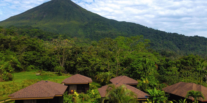 Hotel Lomas del Volcan in La Fortuna, Costa Rica, is a charming and rustic retreat nestled in the lush rainforest at the foothills of the majestic Arenal Volcano. Surrounded by tropical gardens and offering panoramic views of the volcano and the surrounding landscapes, this hotel provides a tranquil and immersive experience in nature. The comfortable and spacious bungalows are designed with a rustic flair, featuring wooden furnishings and private terraces where guests can relax and soak in the natural beauty. The hotel's outdoor swimming pool offers a refreshing respite, while the open-air restaurant serves a variety of delicious local and international dishes. Guests can also take advantage of the hotel's hiking trails, where they can explore the diverse flora and fauna of the rainforest. With its serene setting, friendly staff, and convenient location near Arenal Volcano National Park and other attractions, Hotel Lomas del Volcan offers a memorable stay for nature lovers and adventure seekers in La Fortuna, Costa Rica. Hotel amenities include a bar and restaurant, Spa, swimming pool, Jacuzzi, tropical gardens, yoga deck, conference room and Wifi in most public areas.