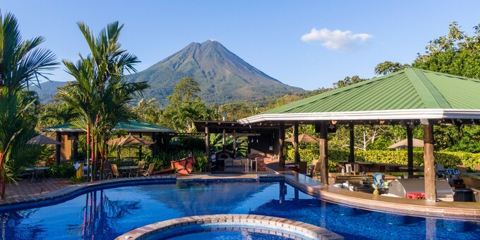 Arenal Manoa Hotel and Spa is a highly rated four-star eco-resort located near Arenal Volcano in La Fortuna, Costa Rica. Guests will be wowed with amazing volcano views, soothing thermal hot springs pools, and excellent customer service. The hotel strives to provide guests with eco-friendly but comfortable accommodations. Hotel amenities include a swimming pool, WiFi, hiking trails, bar, restaurant, hot springs pools, hot tub, tropical gardens, and relaxing spa.