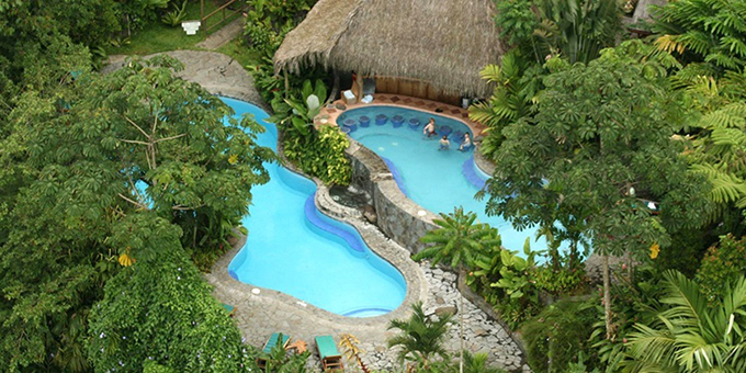 The Lost Iguana Resort Resort and Spa delivers a jungle and rainforest experience unlike any other in the Arenal Volcano area. Set on 120 acres of preserved rainforest near Lake Arenal, this family friendly eco-friendly resort and boutique hotel provides an enchanting setting. The jungle is only steps away from your door, and all rooms have volcano views. Hotel amenities include a full restaurant and bar, tropical gardens, spa, hiking trails, natural frog and bird sanctuaries, a freshwater swimming pool, and a heated swimming pool. The lodge also offers WiFi in some public areas and most rooms. There are golf carts available to use on the premises as some of the rooms are up steep hills. There is no shuttle service to La Fortuna and taxi fares run around $30 each way. Stay includes spa discounts and special surprises from the hotel management. Please be sure to let us know if you are celebrating a special event or special date during your stay.