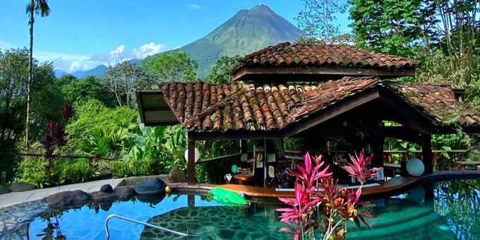 Mountain Paradise Hotel in La Fortuna, Costa Rica, is a captivating mountain retreat nestled in the lush rainforest with stunning views of the Arenal Volcano. The hotel offers a range of comfortable and spacious accommodations, including rooms, villas, and suites, that are elegantly designed and equipped with modern amenities. Guests can enjoy the peaceful ambiance of the surrounding nature from their balconies or terraces. The hotel's outdoor swimming pool provides a refreshing escape, while the on-site restaurant serves delicious Costa Rican and international cuisine. Guests can indulge in relaxation at the spa or take part in thrilling outdoor activities like hiking, canopy tours, and volcano expeditions. Mountain Paradise’s warm thermal pool, reminiscent of a tropical lagoon, is surrounded by nature and features a swim-up bar. The hotel's commitment to sustainability and eco-conscious practices adds to the overall experience. With its serene location, luxurious amenities, and proximity to natural wonders, Mountain Paradise Hotel offers a tranquil and rejuvenating retreat in La Fortuna, Costa Rica. Other hotel amenities include two restaurants, a bar, spa services, and WiFi internet access in some areas.