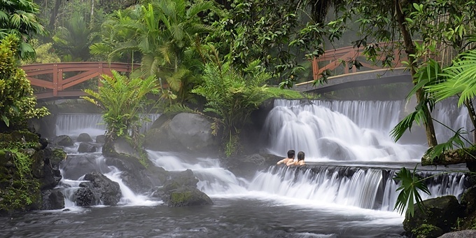 A couple enjoys Tabacon Resort hot springs while on their Costa Rica wellness retreat