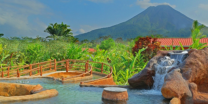 Volcano Lodge in La Fortuna, Costa Rica, is a tranquil, scenic, and affordable retreat located near the renowned Arenal Volcano. Nestled amidst lush tropical gardens, the lodge offers comfortable and spacious accommodations designed to provide a relaxing and immersive experience. Guests can choose from a variety of rooms and suites, all featuring modern amenities with balconies or terraces, most with stunning views of the volcano or the surrounding gardens. The lodge features two outdoor swimming pools, including a thermal mineral pool, where guests can unwind and soak in the therapeutic waters. The on-site restaurant offers a delightful dining experience with a menu inspired by local and international flavors. The lodge's location is ideal for exploring the nearby Arenal Volcano National Park, engaging in adventure activities like hiking and zip-lining, or simply enjoying the serene beauty of the natural surroundings. With its peaceful ambiance, picturesque setting, and warm hospitality, Volcano Lodge provides a perfect escape for guests seeking relaxation and natural wonders in La Fortuna, Costa Rica. Lodge amenities include an onsite restaurant and bar, wet bar, spa, kids pool, and free wireless internet service in some areas.