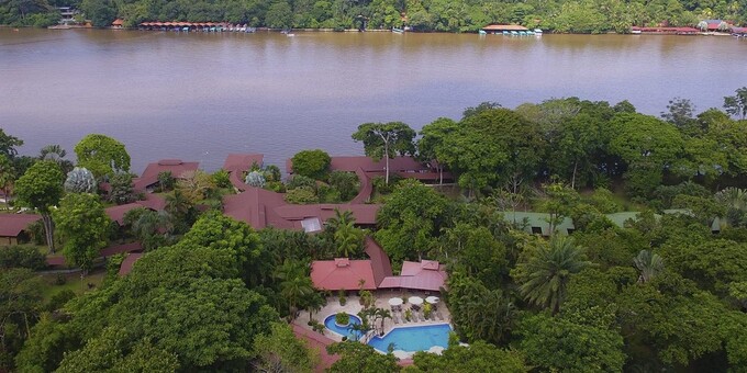 Mawamba Lodge is a tranquil ecolodge retreat nestled within the exotic wilderness of Tortuguero National Park in Costa Rica. Surrounded by lush rainforest and bordered by winding canals, the lodge offers a unique and immersive experience in nature. The lodge's spacious and comfortable bungalows and rooms are designed to blend harmoniously with the natural environment, providing a peaceful and cozy retreat for guests. Each accommodation features modern amenities and terraces or balconies overlooking the gardens or canals. The lodge's restaurant serves a variety of delicious meals, including local and international cuisine, prepared with fresh and locally sourced ingredients. Guests can enjoy their meals while admiring the stunning views of the surrounding nature. Mawamba Lodge offers a range of exciting activities and guided tours, allowing guests to explore the biodiversity-rich rainforest and witness the fascinating wildlife of Tortuguero. Boat tours through the canals offer opportunities to spot monkeys, sloths, toucans, and even nesting sea turtles during the appropriate season. Guests can also enjoy hiking trails, birdwatching excursions, fishing trips, and kayaking adventures. The lodge's swimming pool provides a refreshing oasis where guests can relax and soak up the tropical ambiance. With its commitment to sustainable practices and its privileged location in the heart of Tortuguero, Mawamba Lodge offers an unforgettable experience for nature enthusiasts and eco-conscious travelers. Lodge amenities include a swimming pool and whirlpool, restaurant and bar, coffee room with a put-and-take library, tropical gardens and trails, and WiFi in some public areas. Please note that there is a 15 dollar entrance fee to enter Tortuguero National Park or 5 dollars for kids age 5 to 11. It is not possible to include this in your price as it must be paid in person upon arrival to the area.